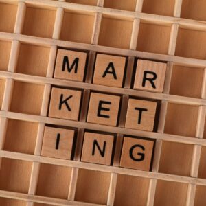 Wooden letter tiles spelling the word MARKETING, representing ad creative and paid media