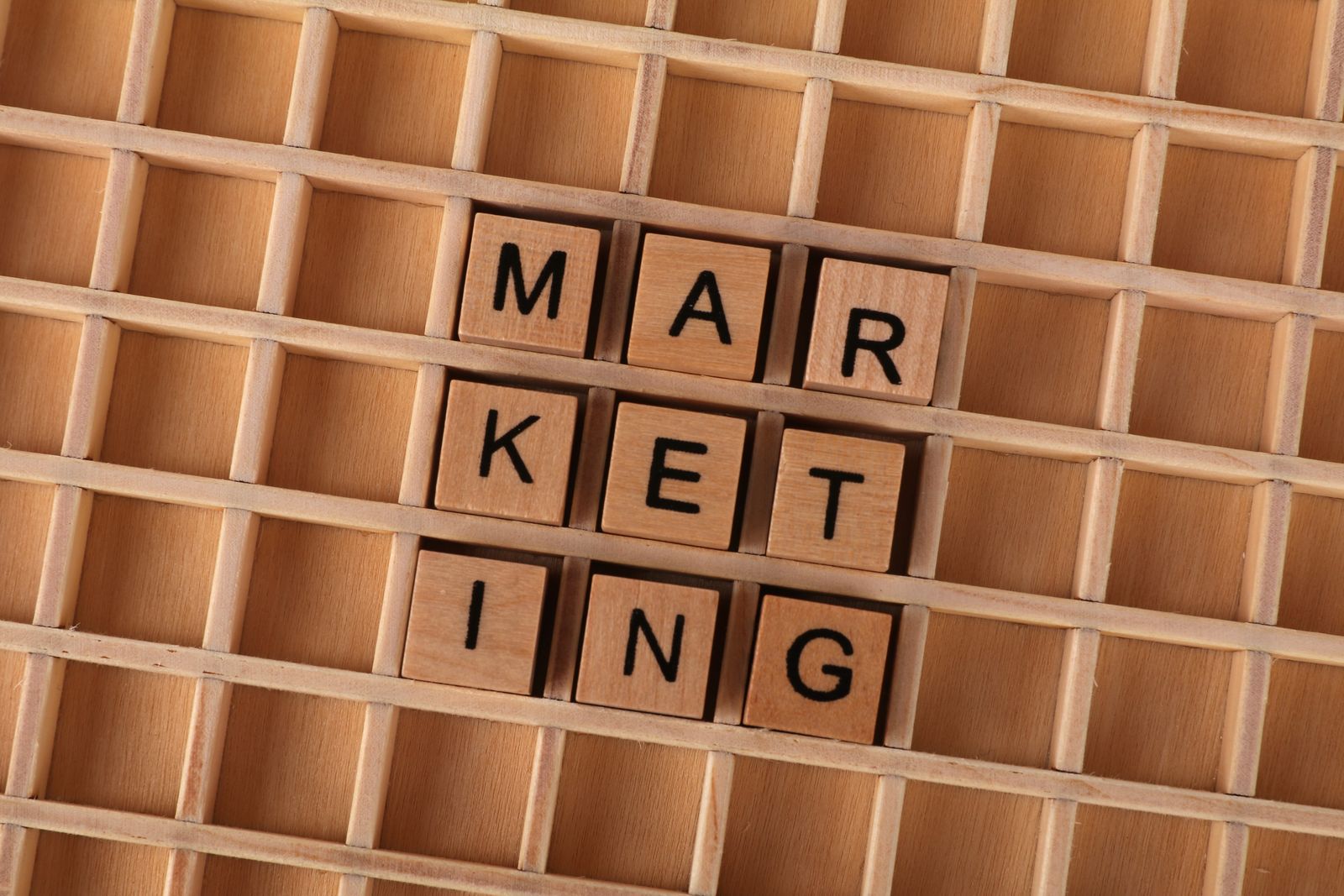 Wooden letter tiles spelling the word MARKETING, representing ad creative and paid media